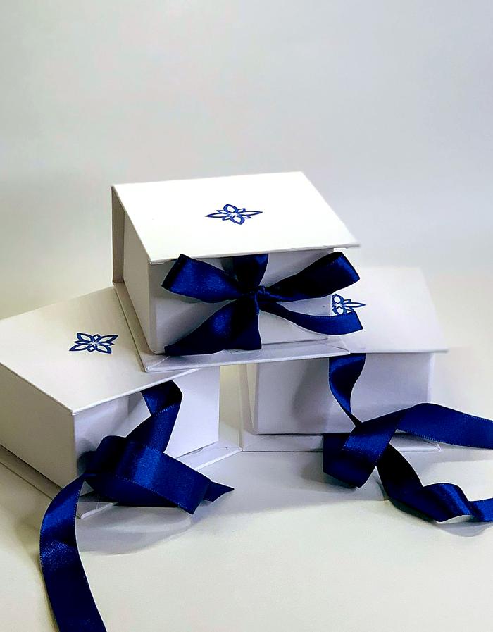 Caixas brancas personalizadas com fita de cetim azul, produção Unibox